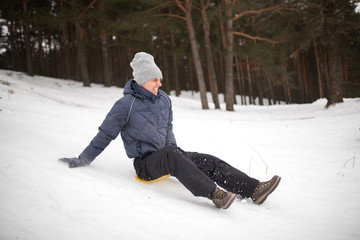 Adult man rides on sled ice from a steep mountain. Winter fun.