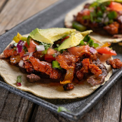 Mexican pork chorizo tacos with avocado and beans on wooden background