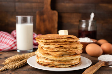 Fototapeta na wymiar Blini, blintzes, russian crepes stacked on plate over rustic composition background. Concept of traditional national holiday Maslenitsa