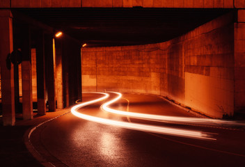 Car light trail under a warm bridge in Catalonia. Urban movement and transportation.