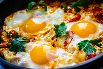Shakshuka - fried eggs with vegetables in frying pan