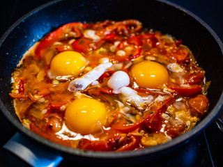 Shakshuka - fried eggs with vegetables in frying pan