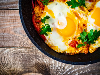 Shakshuka - fried eggs with vegetables in frying pan