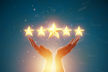 Close-up of a hand and 5 stars, assignment of a new rating, evaluation of services, a new level,...