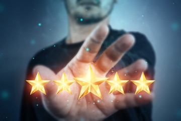 A young man shows 5 stars in the palm of his hand, assigning a new rating, rating services, a new...