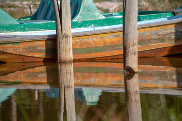 Some old boats and wooden posts on the water of the Las Coloradas lagoon, captured at sunset near the town of Gachantiva in the central department of Boyaca, Colombia.