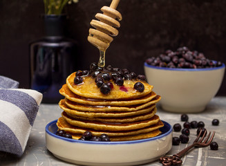 Pancakes with blueberries and honey on a plate.