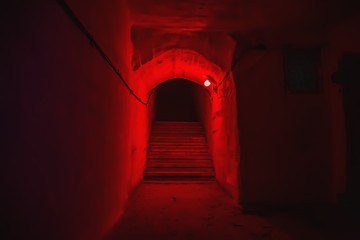Staircase with steps in tunnel of underground military bunker with red light.