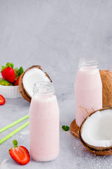 Obraz na płótnie Canvas Strawberry coconut smoothie on coconut milk in a glass jar with a straw on a gray background. Healthy food concept. Vertical orientation, copy space