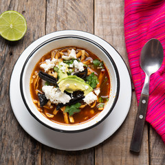 Mexican tortilla soup also called "azteca" on wooden background