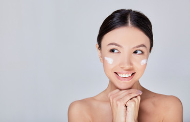 Close-up Portrait of a young gentle Asian woman with cream on her cheeks.