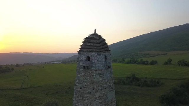 Aeriel video from drone Chechen battle tower at sunset on a background of mountains around greens part3
