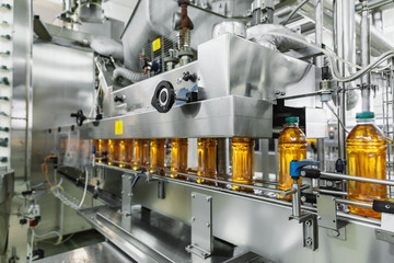 Industrial interior of natural juice plant production. Conveyor belt, filled bottles on beverage...