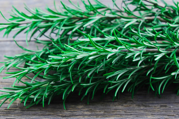 Branches of fresh green bio rosemary lie on a wooden table. Close-up