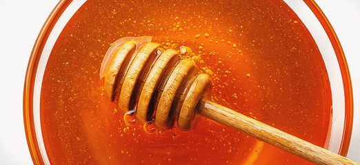Honey pot and dipper on white background, macro photo, top view.