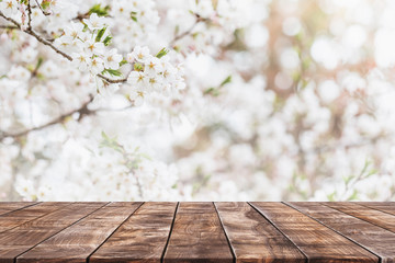 Empty wood table top and blurred sakura flower tree in garden background with vintage filter - can used for display or montage your products.