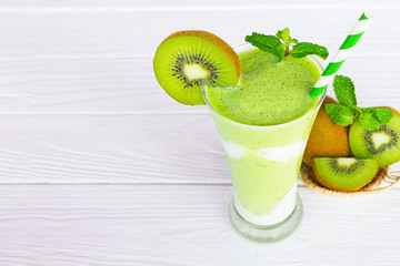 Kiwi yogurt fruit juice smoothie and green kiwi juice drink healthy, delicious taste in a glass for weight loss on a white wooden background.