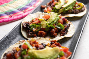 Mexican pork chorizo tacos with avocado and beans on white background
