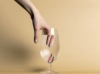 Female hands with nail polsih in a glass with a water