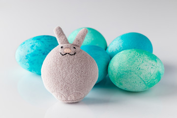 Blue easter eggs and toy rabbit on a white background.