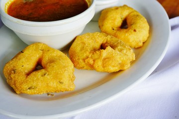 A plate with three Medu Vada donut fritters at an Indian restaurant