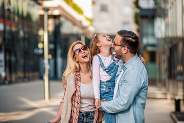  Happy young family of three smiling while spending time together - obrazy, fototapety, plakaty