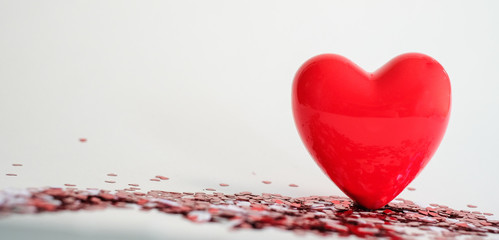 Valentine's Day background . red gloss heart with confetti on pink pastel background with copy space. wedding wallpaper.