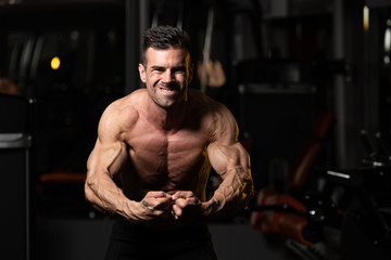 Obraz na płótnie Canvas Muscular Man Flexing Muscles In Gym