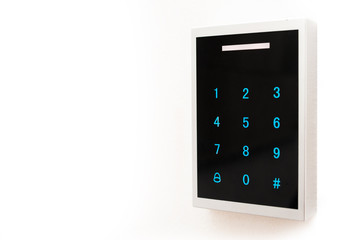 Keypad electronic lock side view. Lock with black glossy front pane and blue dials placed on white wall. Copy space for text.