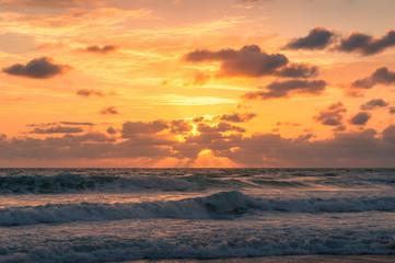 Fototapeta premium Beautiful sunrise seascape with colorful golden orange clouds and soft waves