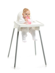 Baby with bottle of milk sitting in high-chair on white background