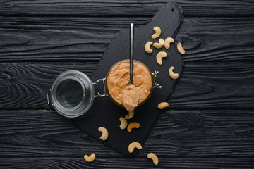 Fototapeta na wymiar Jar of cashew butter on dark wooden background