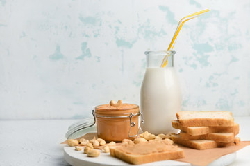 Bottle of cashew milk and bread with nut butter on white background