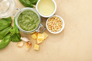 Bowl with pesto sauce and ingredients on color background