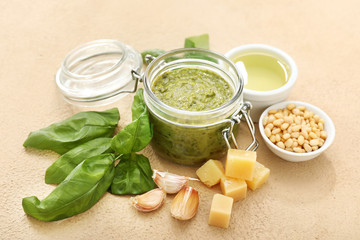 Bowl with pesto sauce and ingredients on color background