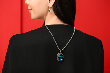 Young woman with beautiful jewelry on color background