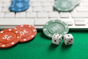 Chips for gambling games, dices with computer keyboard on color background