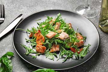 Plate with tasty salmon salad on dark background