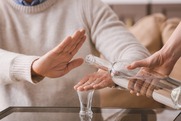 Man refusing to drink vodka at home. Concept of alcoholism