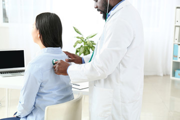 Male cardiologist examining female patient in clinic