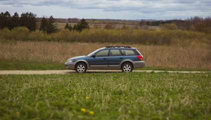 blue suv parked on a gravel road side view