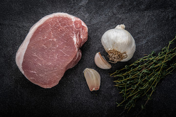 Boneless Center Cut Pork Chop with Thyme and Garlic on a slate background