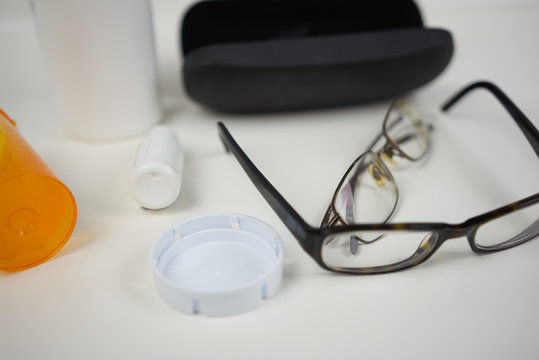 Glasses On White Counter With Various Eye Care Products. Flat Lay Of Medical Supplies For Vision Care