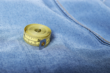 A yellow dressmaker's tape measure on faded blue denim fabric