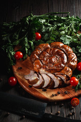Ukrainian traditional semi-smoked sausage with herbs and pepper on rustic wooden background
