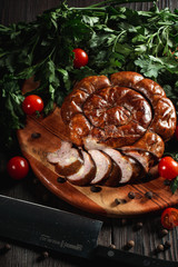 Ukrainian traditional semi-smoked sausage with herbs and pepper on rustic wooden background