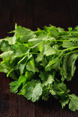 Bundle of fresh raw parsley on dark wooden table close up