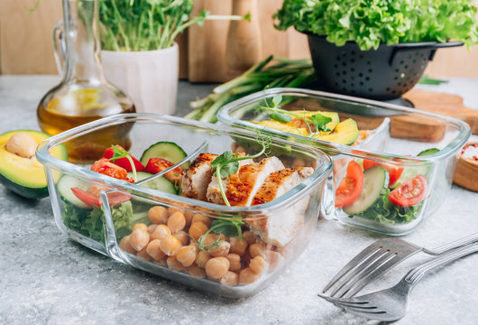 Healthy meal prep containers with chickpeas, chicken, tomatoes, cucumbers and avocados. Healthy lunch in glass containers on light gray background. Zero waste concept. Selective focus.