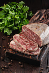 Traditional pork brawn with parsley and pepper on dark wooden board