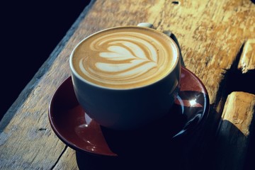 Beautiful heart shaped latte art in a cup at a hipster cafe in the morning sunshine.